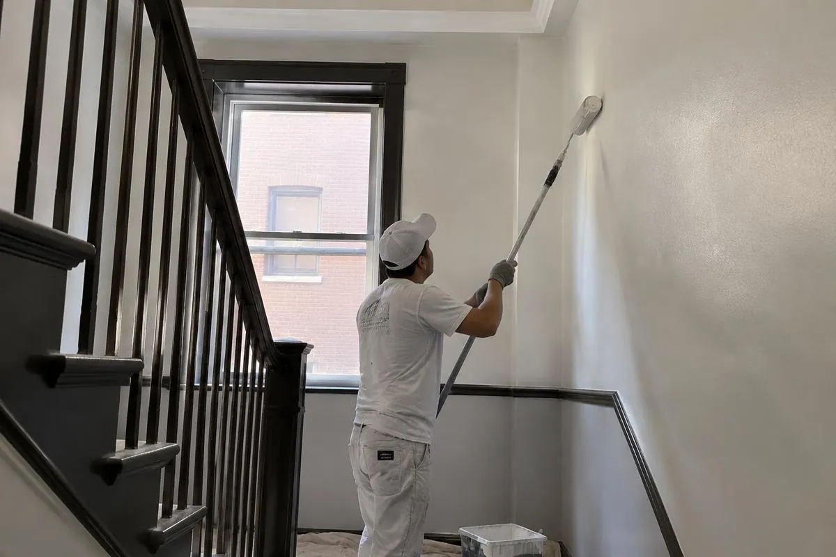 Painter rolling a stairwell wall in an apartment building common area