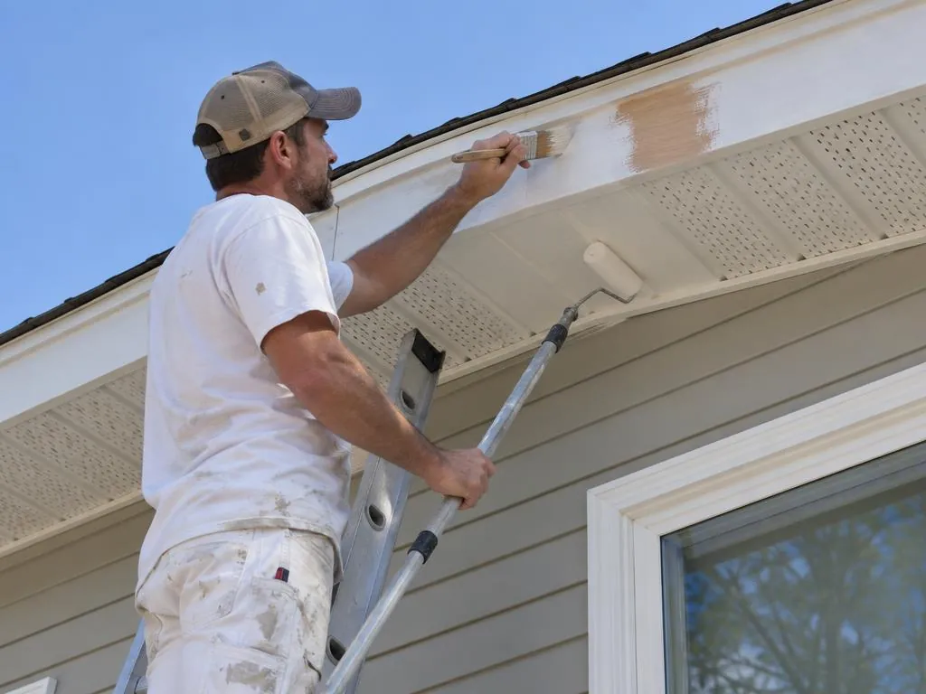 Fascia board and soffit under a roofline being sealed and repainted
